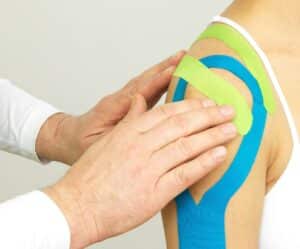 Chiro Taping Therapie mit mehreren farbigen Tapes zur Entlastung der Schulter
